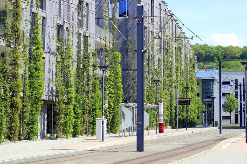 Bâtiment durable avec végétation verticale et arrêt de tram, exemple de développement durable en façade.