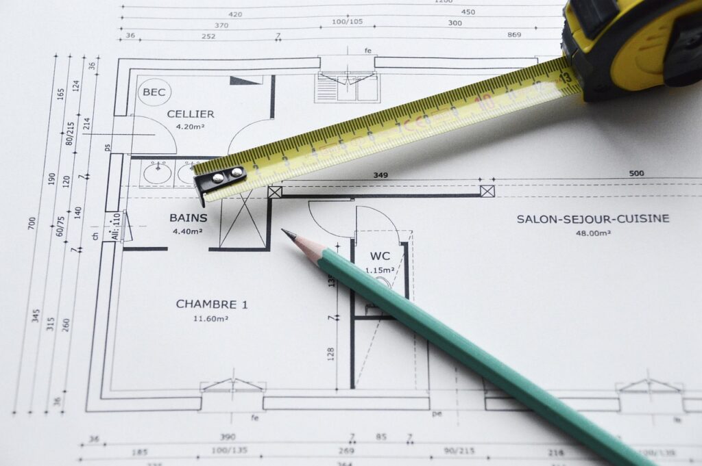 Plan de construction avec des outils, représentant l'importance des devis détaillés pour éviter les litiges entre entrepreneurs et clients.